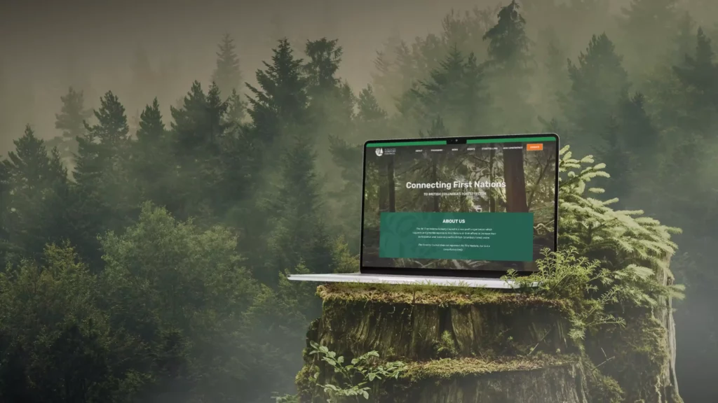 Laptop displaying "Connecting First Nations" website on a mossy tree stump in a foggy forest.