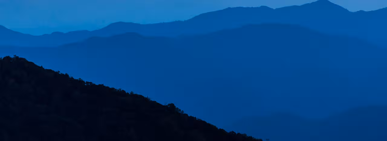Layered blue mountain ranges fade into the distance under a twilight sky.